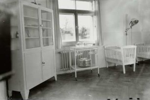 Säuglingsheim. Krankenzimmer mit Instrumentenschrank, Beistelltisch und Gitterbetten für Kleinstkinder