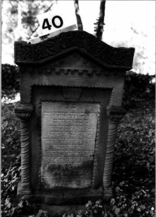 Grabstein 40 (Index: 100106165) Material: Sandstein mit weißer Marmorplatte Zustand: verwittert Maße HxBxT: 95x54x20 cm Beschreibung: ädikulaartige Stele mit gedrehten Halbsäulen, giebelartiger Abschluß mit ornamentalem Aufsatz, Schriftfeld rechteckig: Grabstein 40
