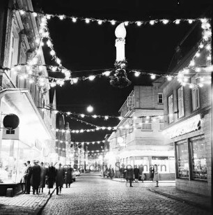 Mühlenstraße mit Adventsbeleuchtung: Passanten und parkende Pkw, links das Kaufhaus Nickel, rechts Einmündung der Hindenburgstraße, Blick Richtung Süden