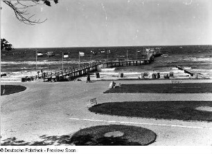 Blick über den Ostseestrand zur Seebrücke mit Flaggen