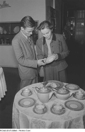 Besucher der Leipziger Herbstmesse 1954 betrachten Porzellangeschirr