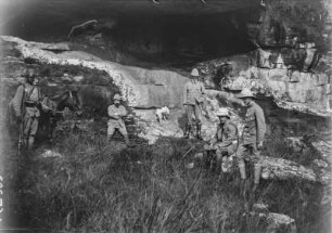 Erkundung einer Höhle : Gruppenportrait einiger Expeditionsteilnehmer vor einer Höhle. Neben ihnen ein deutscher Kolonialsoldat mit Maultier