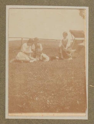 Raimund von Hofmannsthal liegt mit zwei Frauen und einem Mädchen an einem Holzgeländer in Aussee, mit Liegestuhl
