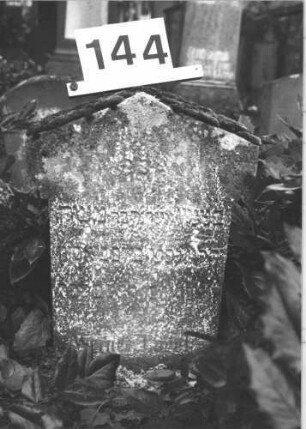 Grabstein 144 (Index: 100114334) Material: Kalkstein Zustand: stark verwittert mit Textverlust Maße HxBxT: 38x36x15 cm Beschreibung: Stele, ausgezogener giebelartiger Abschluß Besonderheit: Kindergrab: Grabstein 144