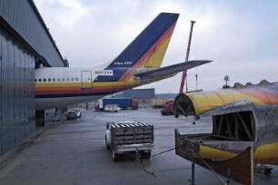 Air Maintenance Services; AMS; Firma; Betrieb; Inspektion; Wartung; spezialisiert auf Flugzeug-Recycling; Airbus; A 300; A300; Airbase Ahlhorn; Ahlhorn; Entsorgung. Ahlhorn, 2006, hier: in dieser Halle wird der Airbus zerlegt werden, das Seitenruder ragt heraus. Der Rumpf eines anderen Airbus liegt vor der Halle