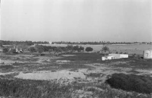 Vor Tripolis : Blick über die Felder einer Plantage und Gebäude vor der Stadt Tripolis