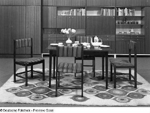 Stuhl mit gepolsterter Sitzfläche und Rückenlehne : Wohnzimmermöbel. Eßtisch und vier Stühle vor einer Anbauwand(1975)
