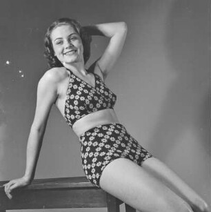 Frau im Bikini sitzt auf einem Tisch