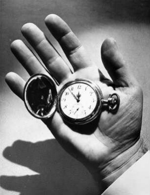 Auf der geöffneten Handfläche liegt eine Taschenuhr. Wie immer ist es kurz vor 12