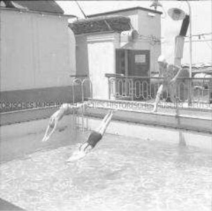 Drei Damen beim Sprung ins Schwimmbecken des Hochseepassagierdampfers "Columbus"
