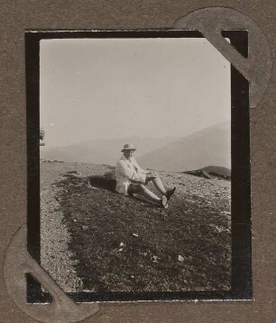 Heinrich Zimmer mit Hut auf einer Wiese in den Bergen sitzend