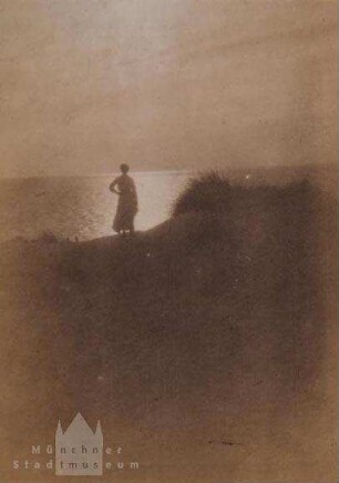 Frau auf Dünen stehend, auf das Meer blickend