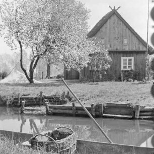 Strohgedecktes Blockhaus mit Anlegerstelle. : Ze słomu kryta kładźita chěža z přistawnišćom.