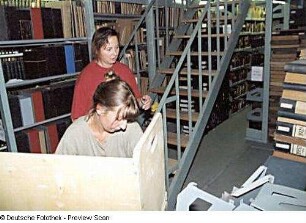 Sächsische Landesbibliothek - Staats- und Universitätsbibliothek Dresden. Zentralbibliothek (ehem. Landesbibliothek). Umzugsvorbereitungen im Magazin-Flachbau (Erdgeschoss). Hilfskräfte beladen einen Bücherwagen : Dresden-Neustadt, Marienallee 12. Sächsische Landesbibliothek - Staats- und Universitätsbibliothek Dresden. Zentralbibliothek (ehem. Landesbibliothek). Umzugsvorbereitungen im Magazin-Flachbau (Erdgeschoss). Hilfskräfte beladen einen Bücherwagen