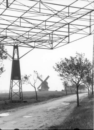 Moritzer Mühle (Turmwindmühle) und Mühlengehöft. Im Vordergrund Schutzgitter unter einer Freileitung über einem Fahrweg : Zeithain. Moritzer Mühle (Turmwindmühle) und Mühlengehöft. Im Vordergrund Schutzgitter unter einer Freileitung über einem Fahrweg