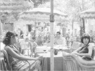 Zwei junge Frauen trinken Wein auf der Terrasse eines Cafés