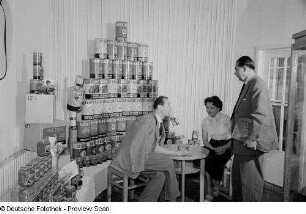 Personen vor Lebensmittelkonserven der belgischen Sektion auf der Leipziger Herbstmesse 1954