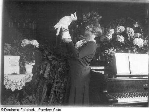 Elisabeth Rethberg mit Blumenarrangement und Geschenken : Porträt Elisabeth Rethberg aus feierlichem Anlaß mit Blumenarrangement und Geschenken in ihrer Wohnung. Fotografie von Ursula Richter, um 1928
