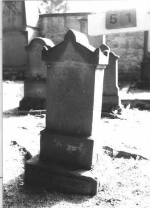 Grabstein 51 (Index: 100105668) Material: Sandstein Zustand: vollständig verwittert Maße HxBxT: 90x35x19 cm Beschreibung: Stele, getreppter Sockel, Giebel mit Akroteren: Grabstein 51