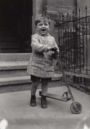 Kinderfoto des Fotografen Günther Hanisch mit Holzroller vor dem Hauseingang