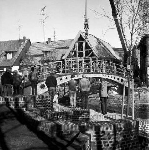 Trave: Stadtarm: Bau der Brücke zwischen der Hude und Heiligengeiststraße: ein Krangerät hebt die Brücke ein, vorne Personen, im Hintergrund Gebäude der Heiligengeiststraße, Blick nach Nordwesten