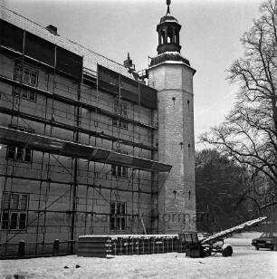 Restaurierung: Gerüst an Fassade: im Winter: davor Stapel mit Dachziegeln, Transportband, Auto