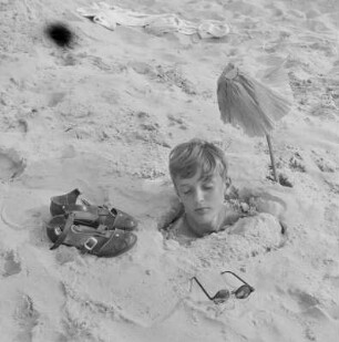 Junge ist bis zum Kopf im Sand vergraben