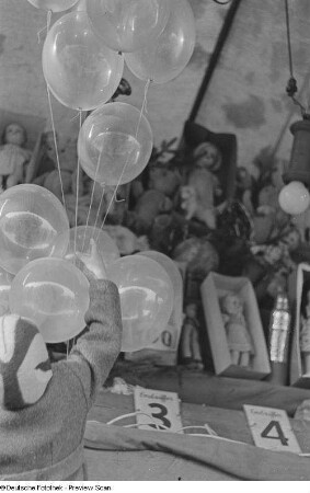 Kind an einem Losstand nach Luftballons greifend