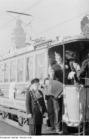 Musizierende Karnevalisten und Personal auf einer geschmückten Straßenbahn