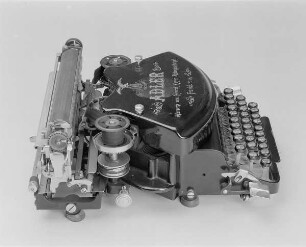 Stoßstangenschreibmaschine "Adler" (Modell 7). Vorderanschlag (sofort sichtbare Schrift), 30 Tasten, doppelte Umschaltung, Farbband. Seitenansicht von links oben : Stoßstangenschreibmaschine "Adler" (Modell 7). Vorderanschlag (sofort sichtbare Schrift), 30 Tasten, doppelte Umschaltung, Farbband. Seitenansicht von links oben. Baujahr: 1899 oder 1900; Hersteller: Adlerwerke vormals Heinrich Kleyer AG Frankfurt (Main); Verwalter: Sächsische Landesbibliothek - Staats- und Universitätsbibliothek Dresden (SLUB), Stenografische Sammlung, Inventar-Nummer R i 0001
