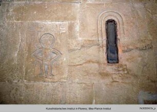 Figur zwischen zwei Kreuzen und Rosetten