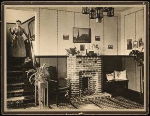 Wohnhaus Wolkenstein Bellevuestraße 70, Berlin-Lichterfelde (?): Diele mit Kamin, Frau mit Besen auf dem Treppenaufgang