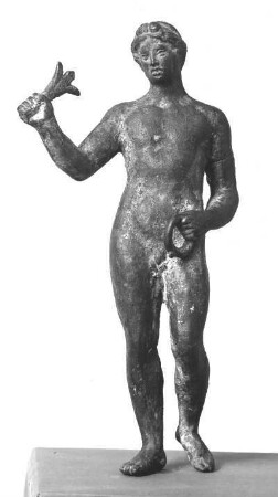 Statuette eines nackten Jünglings, auf dem Kopfe über der Stirn eine Haarschleife (?), in der erhobenen L. und der ein wenig vorgestreckten R. je ein Rest eines unbestimmbaren Gegenstandes (Attributs)