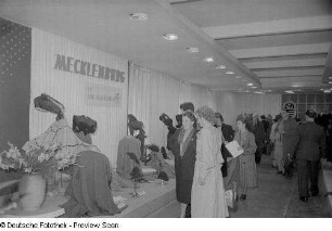 Besucher an einem Messestand mit Textilien (Damenoberbekleidung)