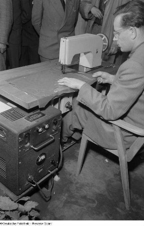 Ein Mann führt die Nahtschweißmaschine des Unternehmens Rundfunk- und Fernmelde-Technik (RFT) vor, Technische Messe 1953