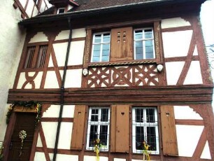 Kurmainzisches Schloß-Innenhof nach Norden-Fachwerkgebäude (Riegelbauweise) über Traufseite mit ornamentierenden Holzschnitzereien in Farbigkeit sowie zwei Schreck- oder Schutzköpfen
