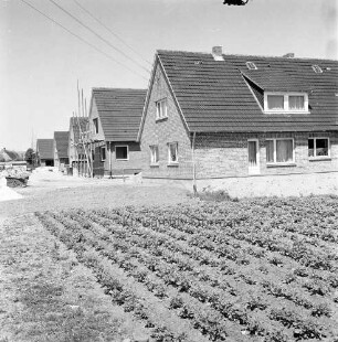 Baustelle von Wohngebäuden, vorne rechts ein Beet