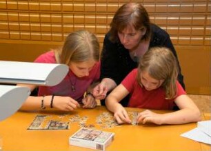 Kinder bei der "Bibliotheksrallye für Kinder" (Kinder lernen die Bibliothek spielerisch auf einer Rallye kennen. Die Maya-Zahlen weisen den Weg) im Serviceraum der Deutschen Fotothek