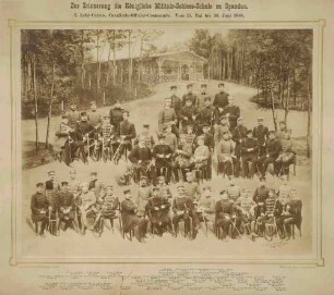 Teilnehmer (ca. zweiundfünfzig Personen) am Lehrkurs der Militär-Schiessschule Spandau in Waldlichtung teils stehend, teils sitzend, im Hintergrund eine Hütte