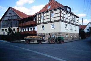 Bauernhof: Wohnhaus mit Sichtfachwerk im OG; Traktor mit Hänger und Kartoffelsäcken