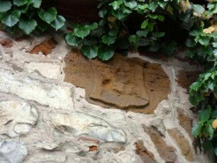 Kirchhofmauer im Südwesten-verwittertes Wappen unter Fachwerkobergeschossen des Frühmessnerhauses (auf Kirchhofmauer aufgebaut)