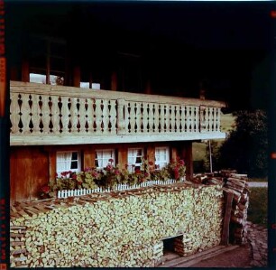 Gschwend: Schwarzwaldhaus, Holzstapel am Blumenfenster
