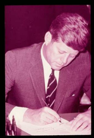 John F. Kennedy, unterschreibt am Schreibtisch