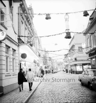 Mühlenstraße mit Adventsbeleuchtung: Passanten und parkende Pkw, links das Kaufhaus Nickel, rechts Einmündung der Hindenburgstraße, Blick Richtung Süden