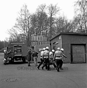 Glinde: Gelände der Jurid-Werke GmbH: Kreiskatastrophenübung mit Freiwilligen Feuerwehren, Technischem Hilfswerk (THW), Deutschem Roten Kreuz, Malteser Hilfsdienst, Arbeiter-Samariter-Bund (ASB) und Spezialeinheiten: in der Mitte Feuerwehrmänner beim Transportieren eines Generators: links dahinter Löschwagen mit Feuerwehrmann: rechts dahinter Firmengebäude