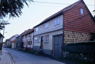 Dorfstraße, dichte Zeile traufständiger Häuser, das erste mit Ziegelverhang am Giebel