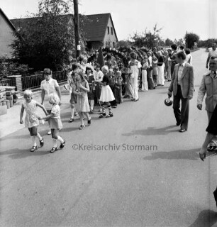 Dorffest der Dorfgemeinschaft Klein Wesenberg: Festumzug der Kindergruppen mit Blumenbögen: hinten Häuser und Gärten