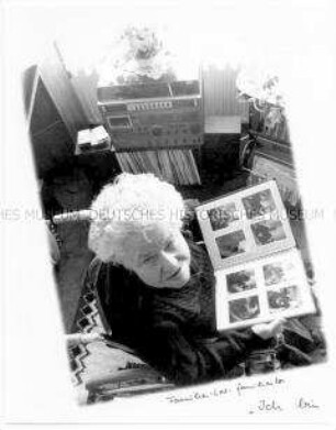 Alte Frau im Rollstuhl aus der Vogelperspektive fotografiert, schaut sich ein Fotoalbum an (Sonderthema: Familienbilder)