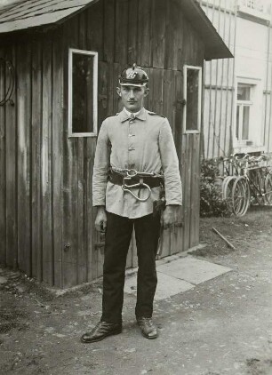 Feuerwehrmann mit Uniform, Helm und Sicherheitsgürtel mit Karabinerhaken und Feuerwehrbeil