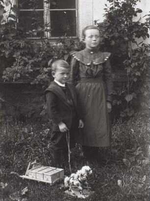 Mädchen und kleiner Junge mit Spielzeugpferd und -wagen